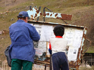 Un uomo e un bambino leggono i manifesti funebri esposti pubblicamente